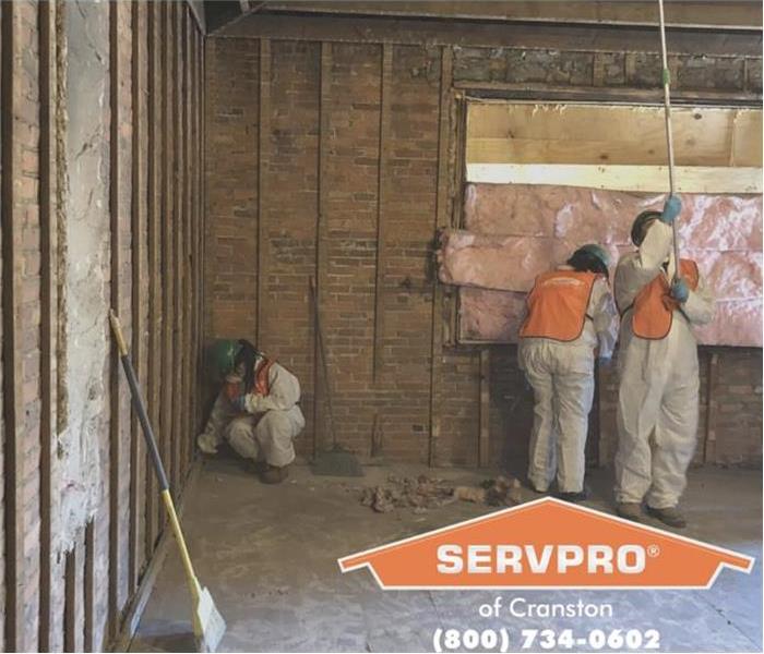 Three technicians, cleaning the ceiling of a commercial property, removing insulation from wall, cleaning baseboard